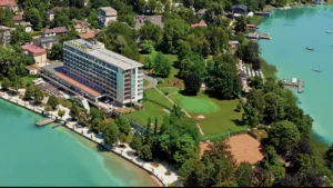 Luftaufnahme vom Hotel in Pörtschach direkt am Wörthersee gelegen mit Strandzugang und Steg in den See, Grünanlage um das Hotel